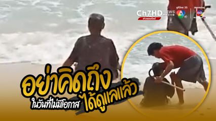 ลูกหลานพาคุณยายไปเที่ยวทะเล คุณยายนั่งเล่นเหมือนเด็กๆ ดูมีความสุข โดยมีลูกยืนดูแลไม่ห่าง